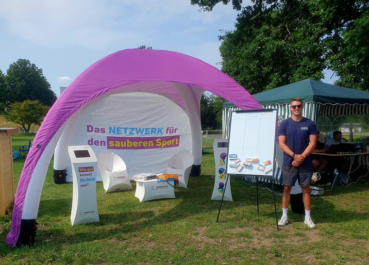 Ein Infostand von 'GEMEINSAM GEGEN DOPING' draußen.