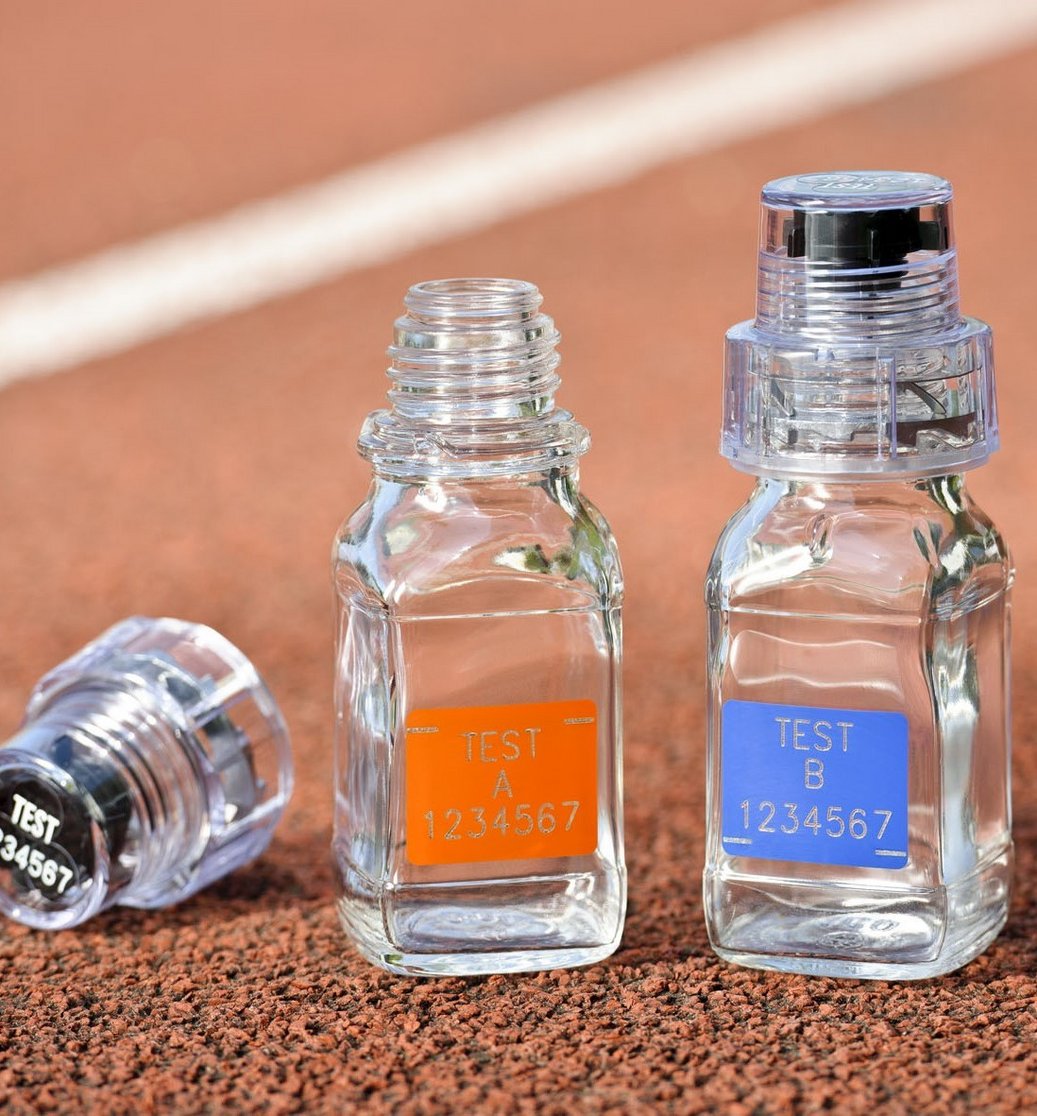 Leere Testflaschen zur Dopingkontrolle auf einer Laufbahn. Das Foto veranschaulicht die Thematik der Probeentnahmen für Dopingkontrollen.
